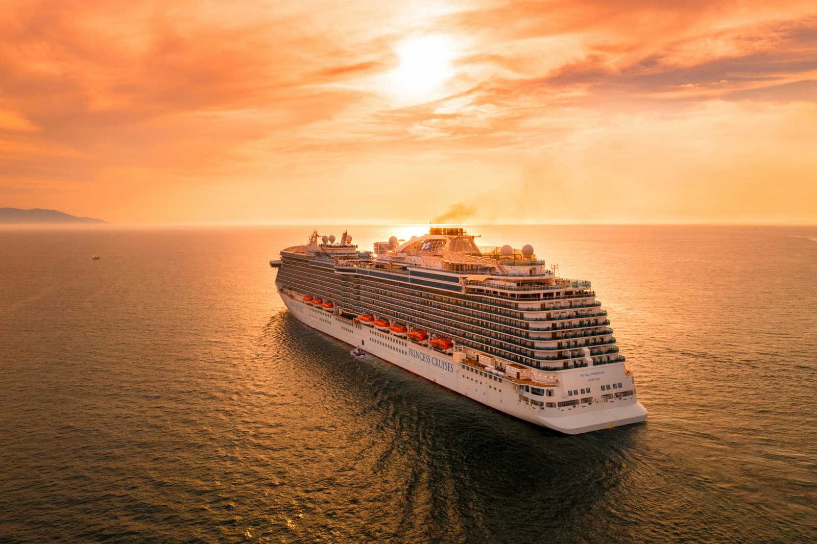 White cruise ship sailing at sea during sunset.