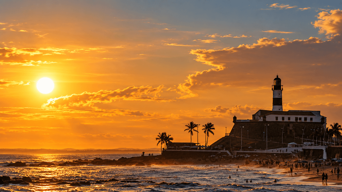 Farol da Barra silhouetted above the beach and Atlantic Ocean at a golden sunset in Salvador.
