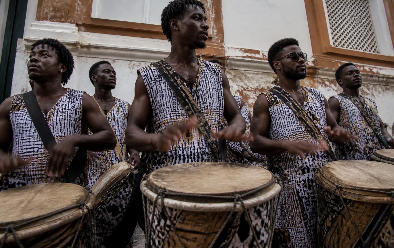 Percusionistas de un bloco afro tocando tambores frente a un muro colonial en Salvador.