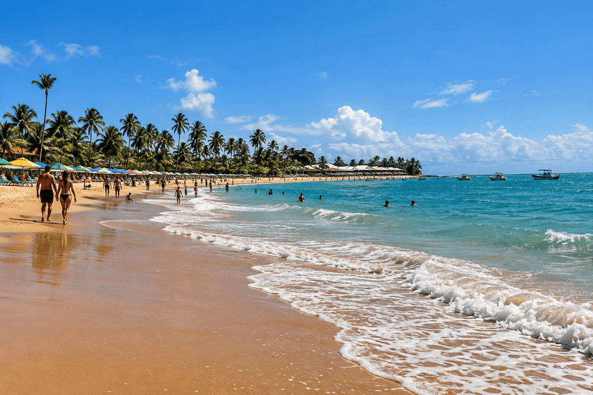 Wide view of Guarajuba beach with golden sand, palm trees, swimmers and blue-green Atlantic water.