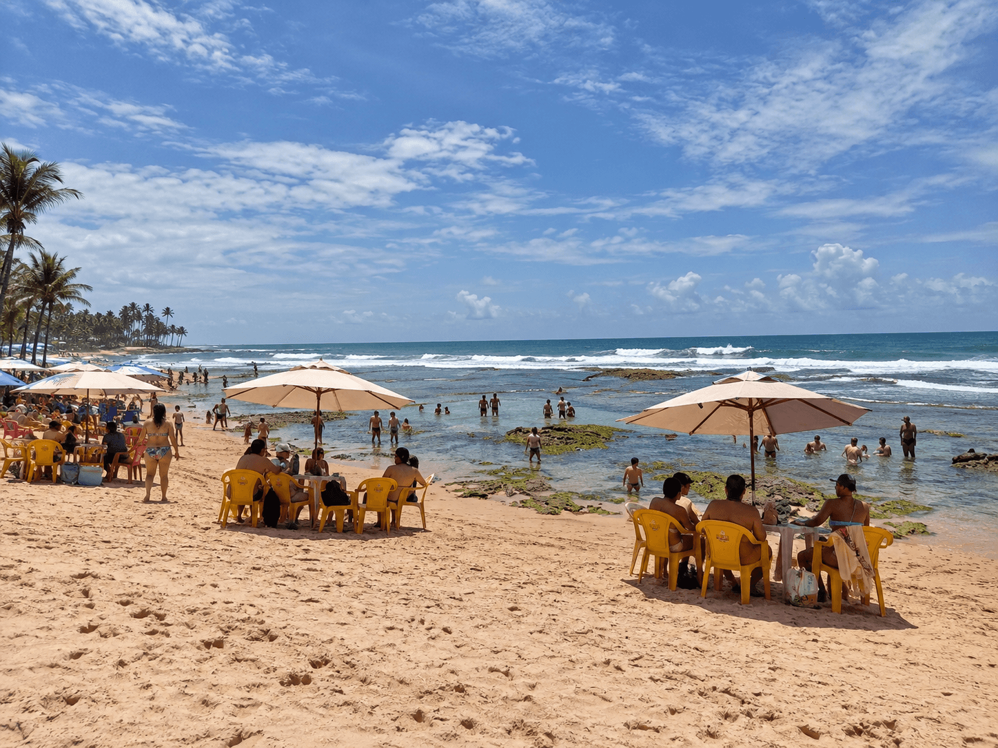 Playa de Stella Maris en Salvador, con sombrillas, visitantes y piscinas naturales entre las rocas.
