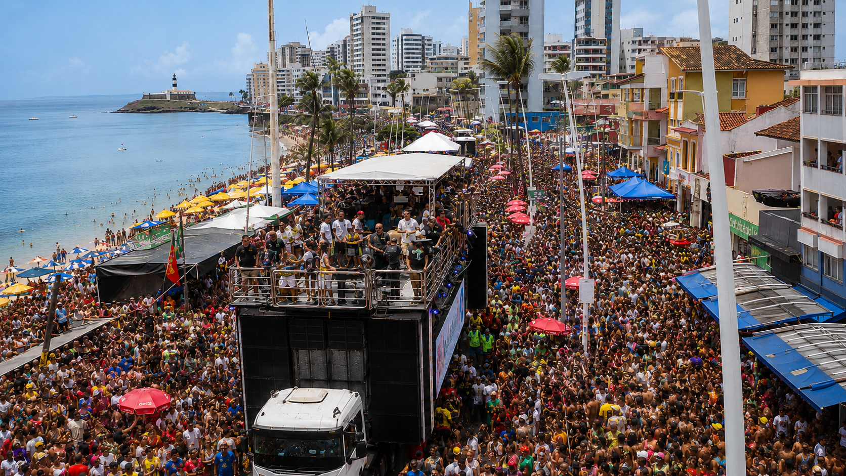 Un trio elétrico avanza entre la multitud del Carnaval de Salvador en la costa Barra-Ondina, con el Farol da Barra visible a lo lejos.